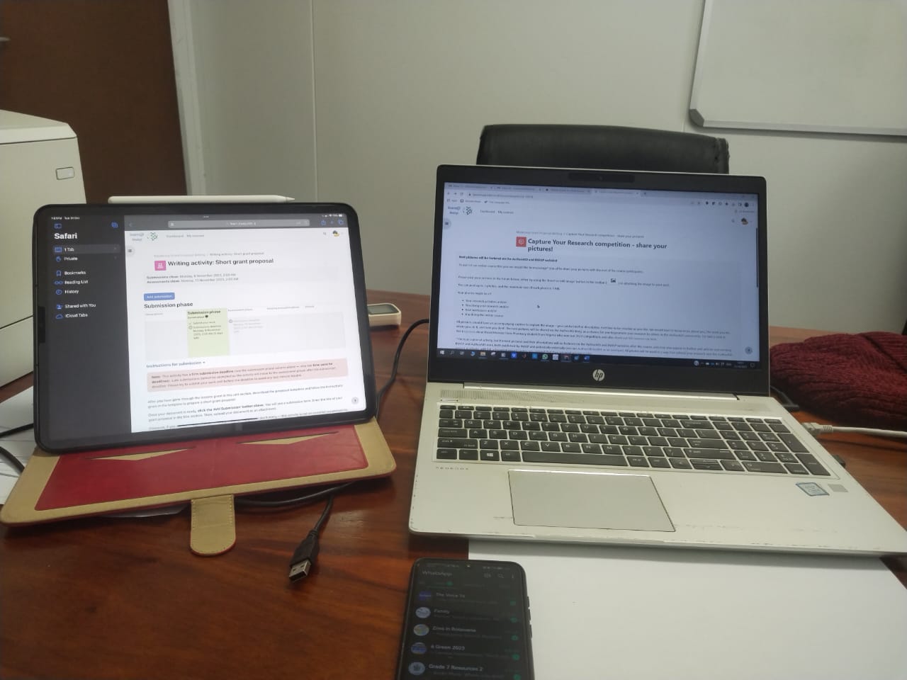 An open laptop showing the Capture Your Research Contest page of an AuthorAID MOOC open, next to a tablet that is open on an activity page of an AuthorAID MOOC. The devices are on a desk, along with a smartphone. 